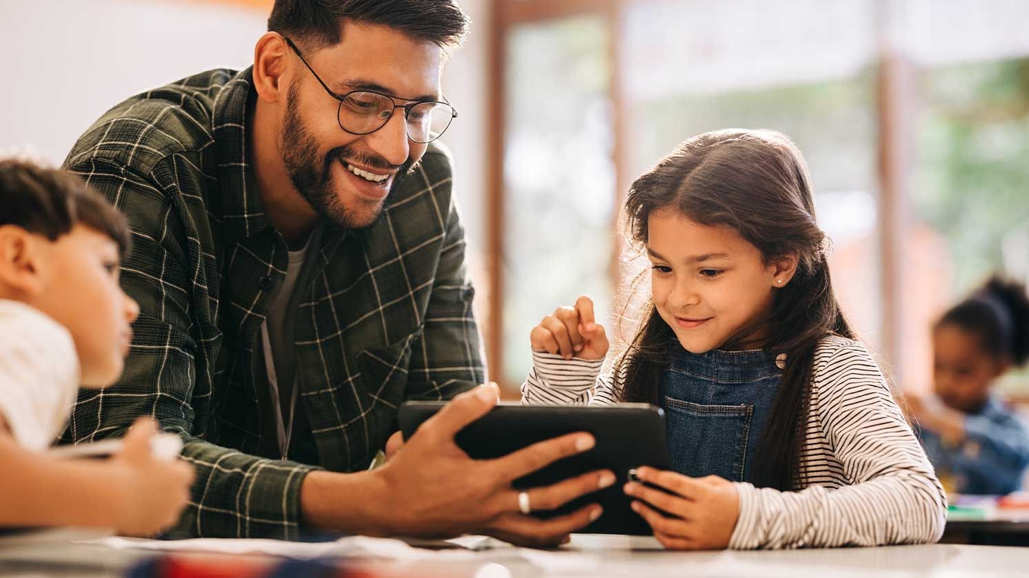 Ein Lehrer hilft einer Schülerin am Tablet