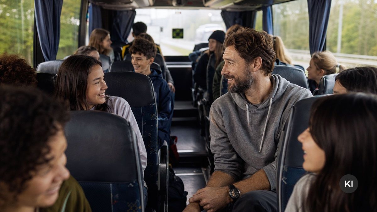 Eine Schuklasse sitzt mit ihrem Lehrer in einem Reisebus.